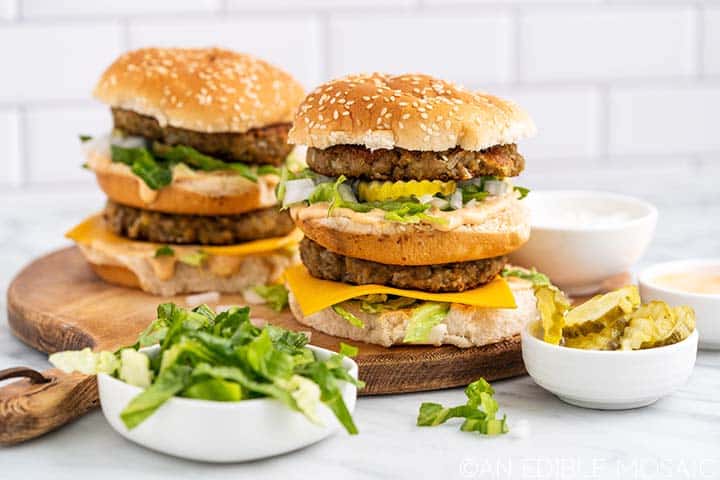 vegan big macs on wooden board with toppings