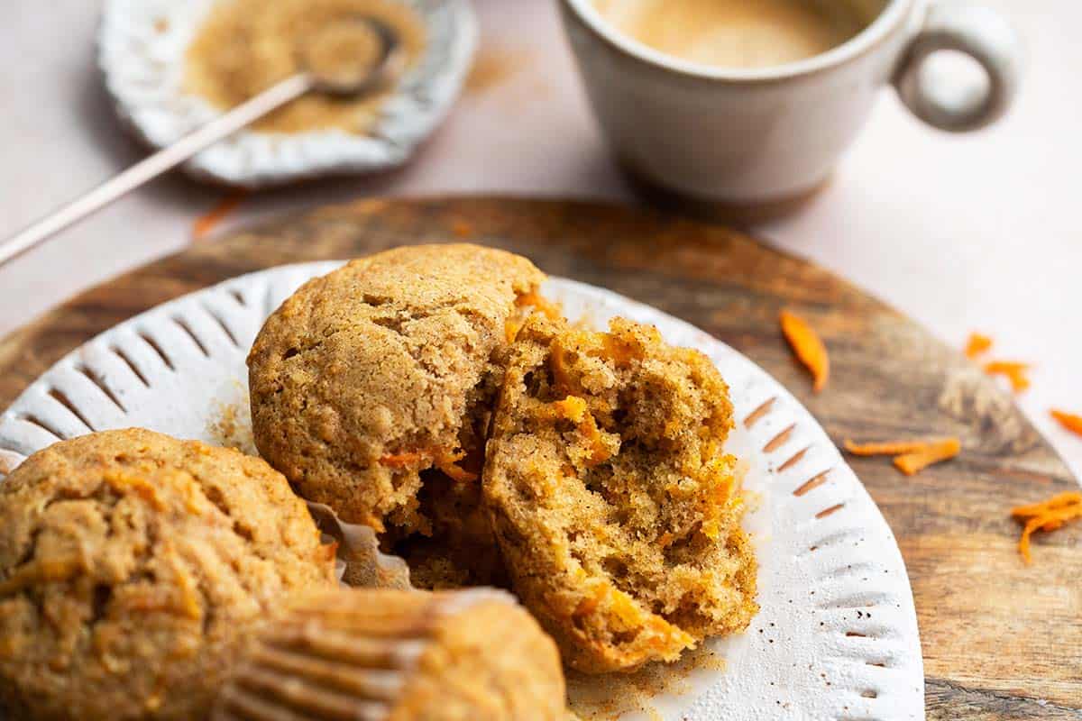 front view of carrot muffins on plate with one split in half showing soft fluffy texture