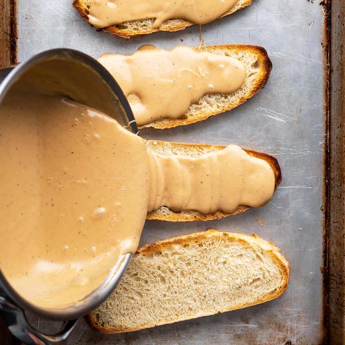 pouring cheese sauce on toast for welsh rarebit featured image