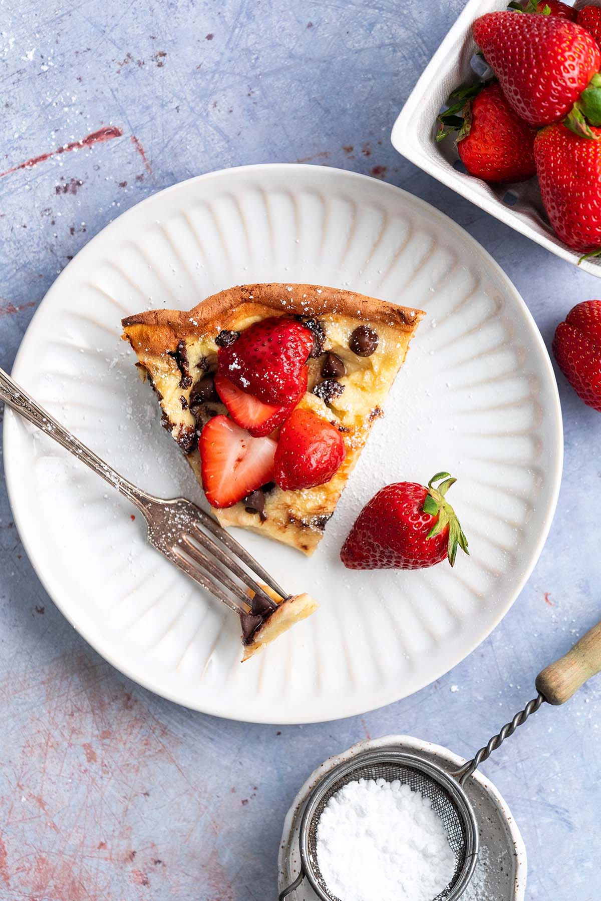 top view of slice of dutch baby pancake on plate with bite on fork