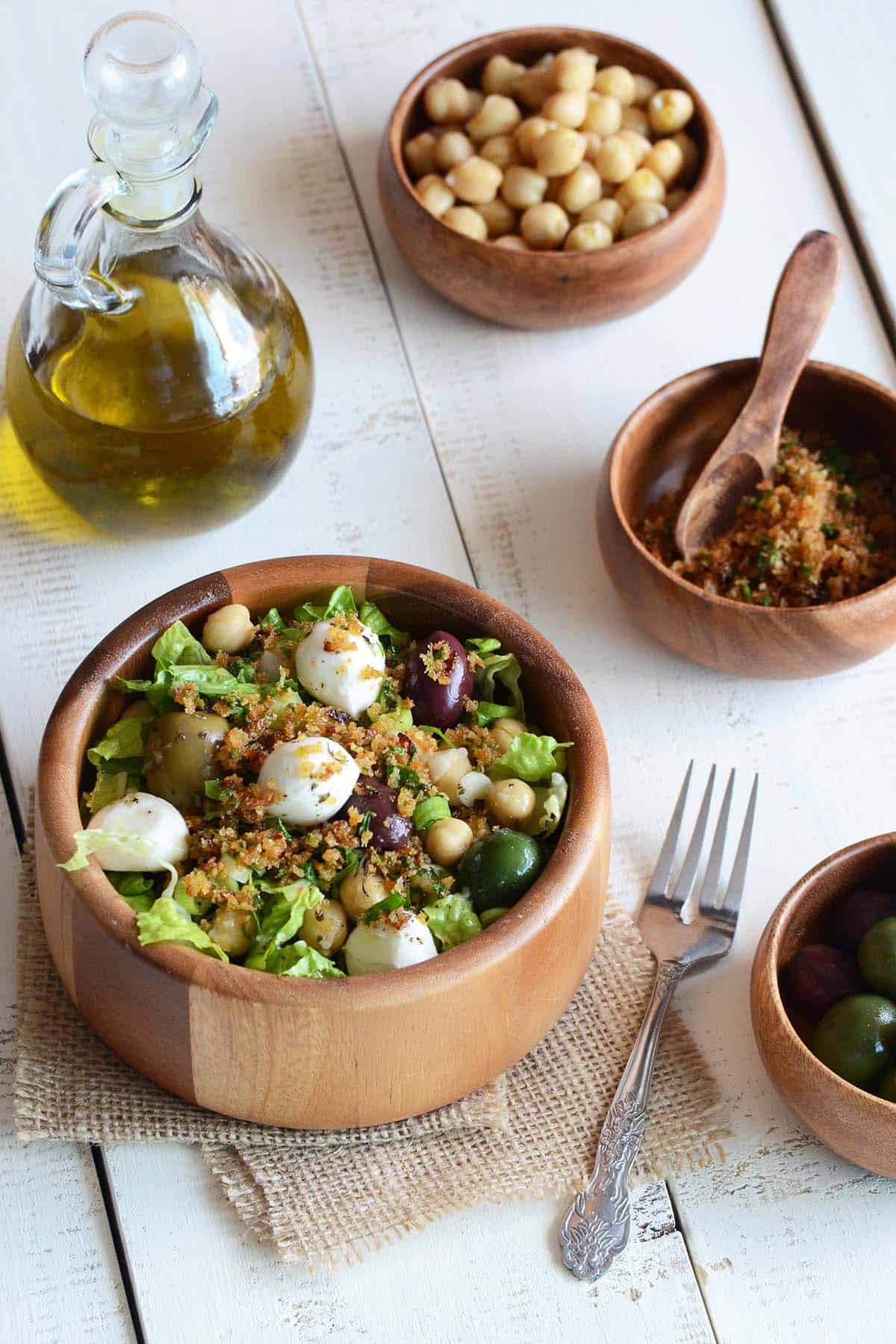 bread crumb salad in wooden bowl with jug of olive oil and other ingredients around