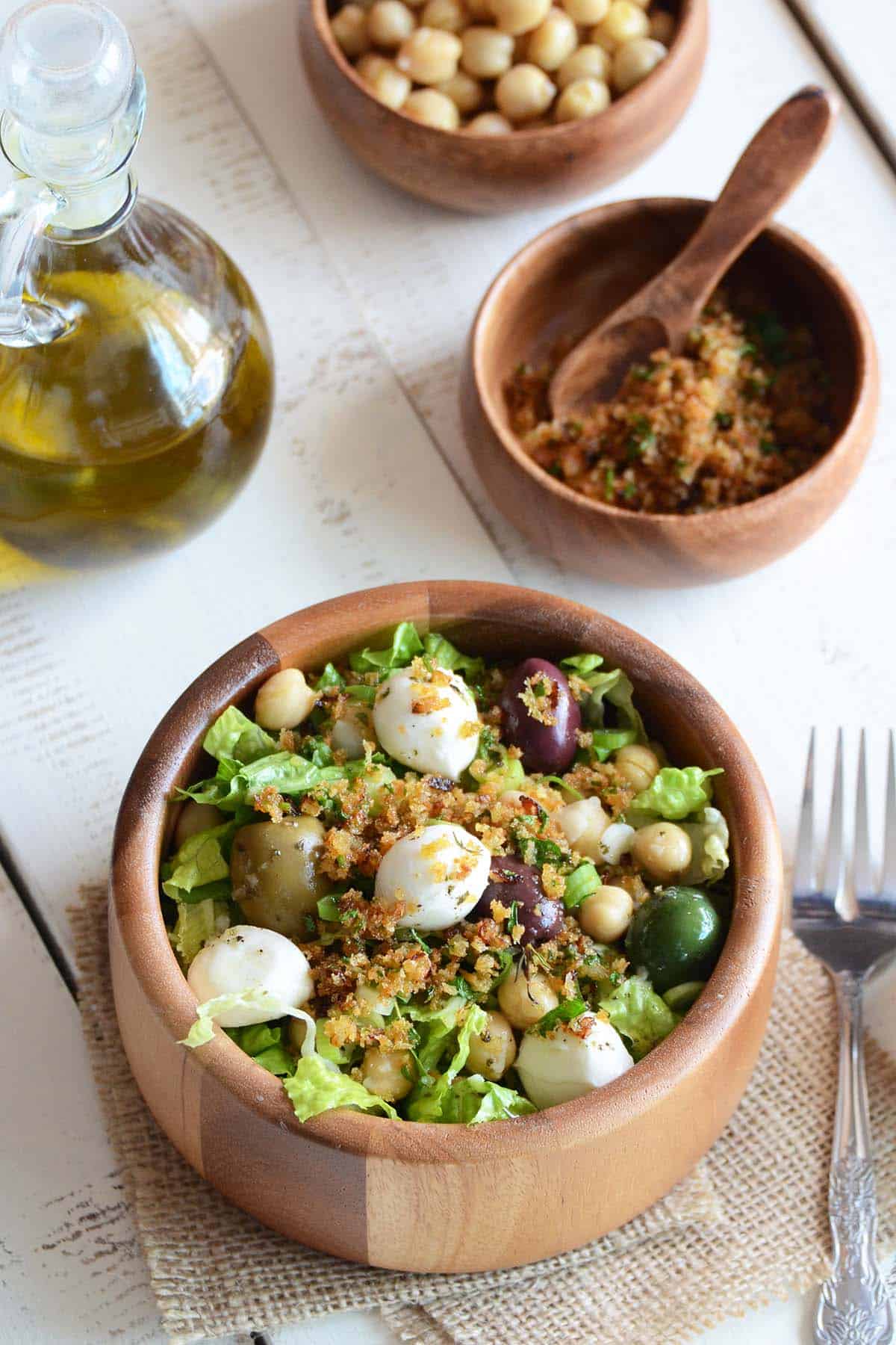 romaine lettuce salad with bread crumb topping in wooden bowl on white wooden table