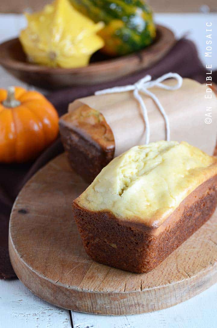 Two Loaves of Pumpkin Bread on Cutting Board with Colorful Gourds