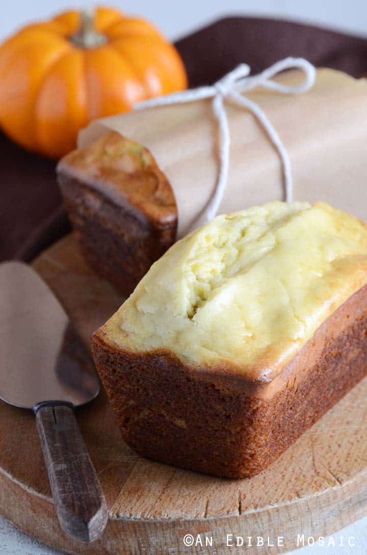 Loaves of Pumpkin Cheesecake Bread with Baby Pumpkin on Wooden Cutting Board