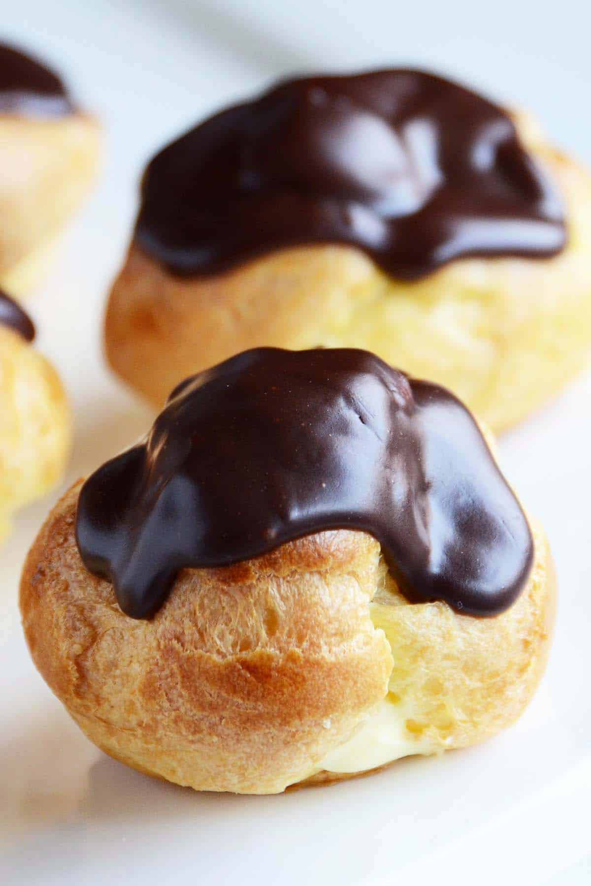 close up front view of custard filled profiterole with chocolate ganache topping