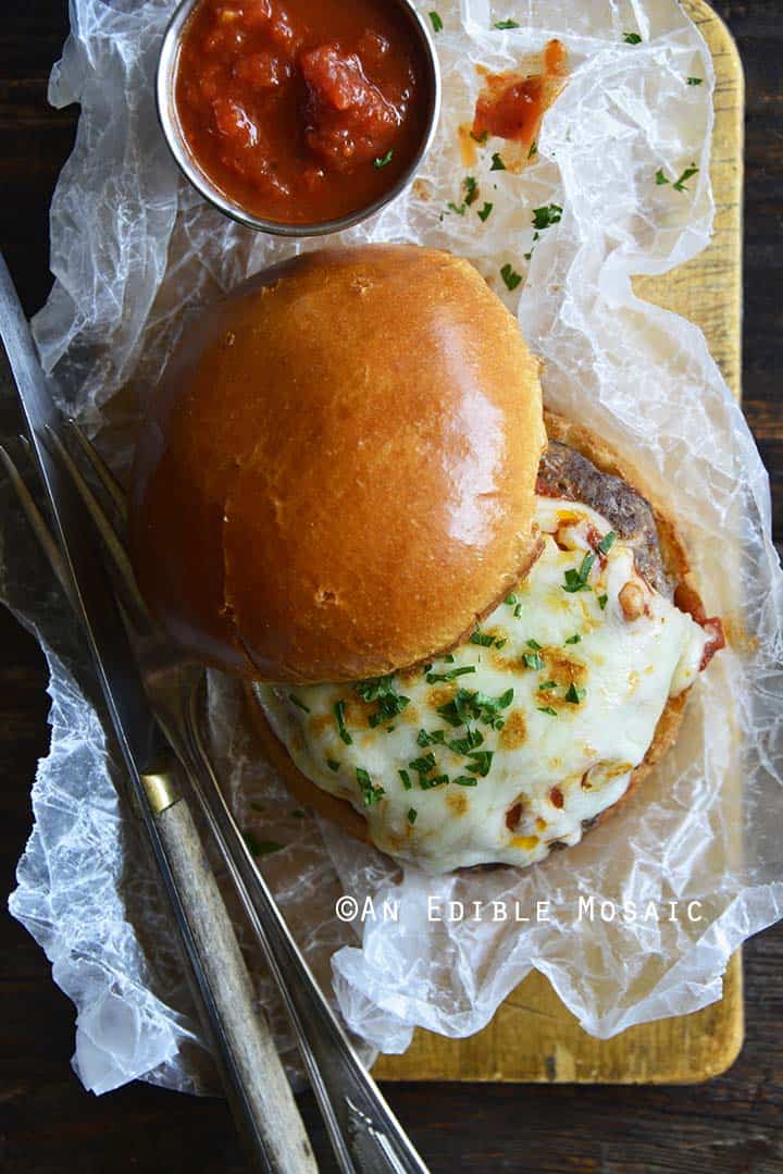 Overhead View of Pizza Burger on White Wax Paper on Wooden Board