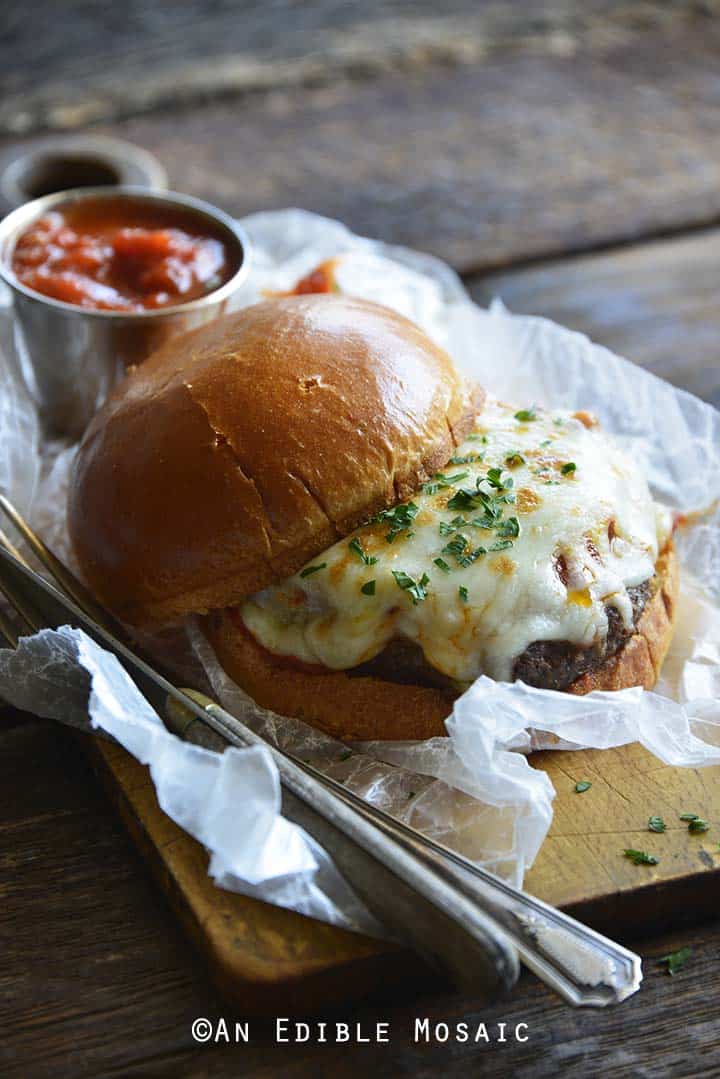 Pizza Burger with Vintage Knife and Fork on Wooden Board with Chunky Marinara Sauce