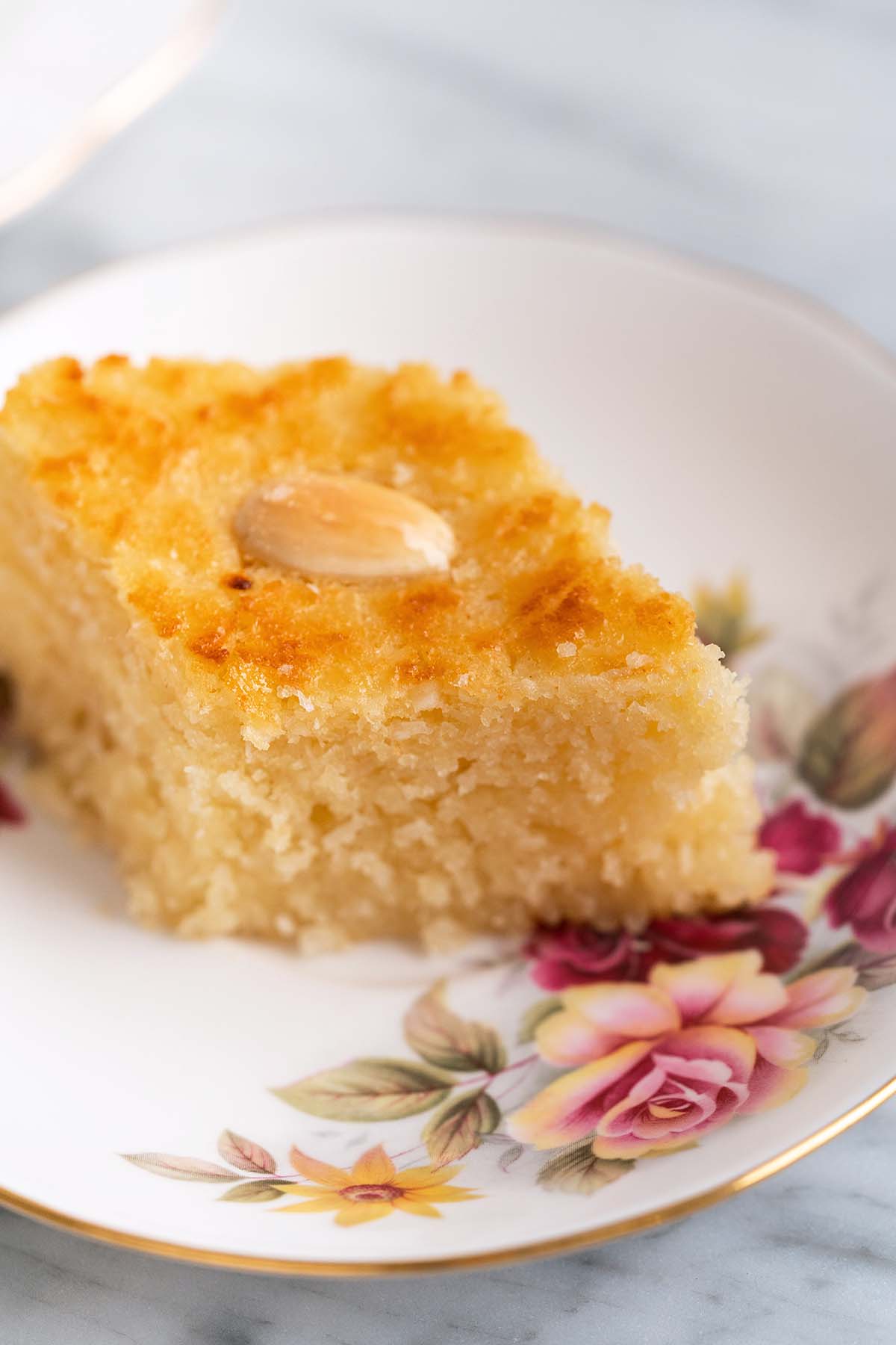 close up front view of moist basbousa cake on rose plate