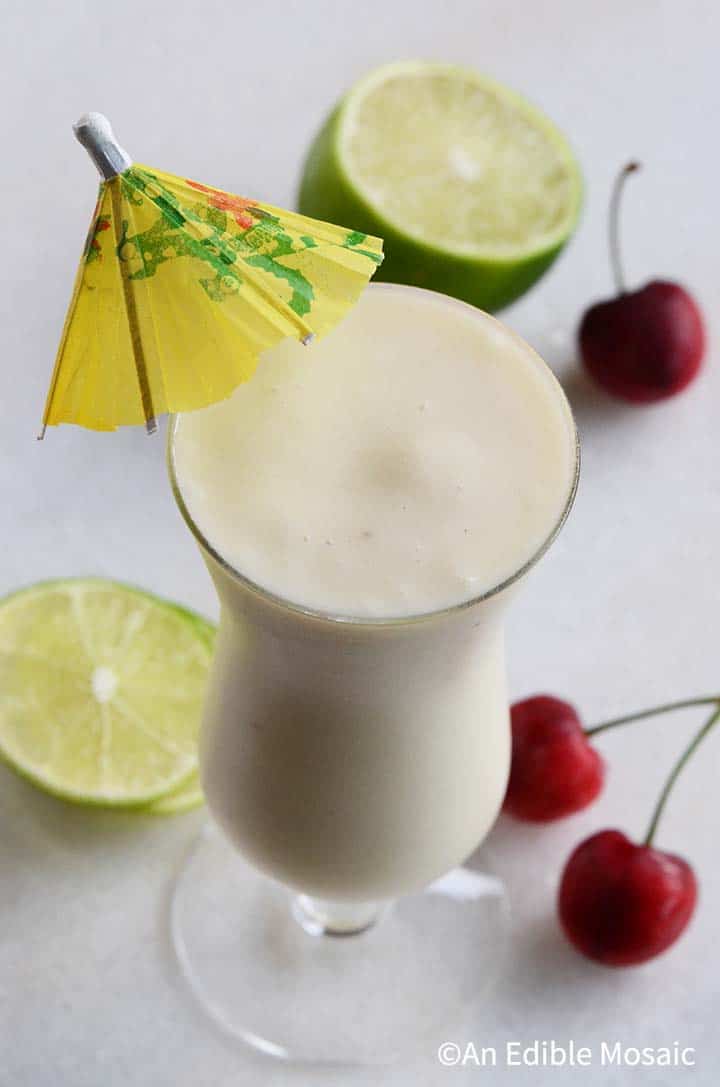 Pina Colada Drink on White Marble Countertop with Lime and Fresh Cherries