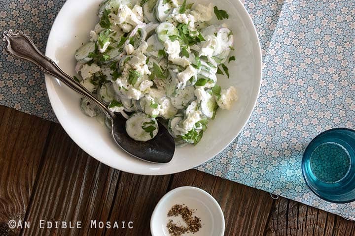Creamy Cucumber Salad in White Dish with Vintage Spoon on Blue Flowered Fabric