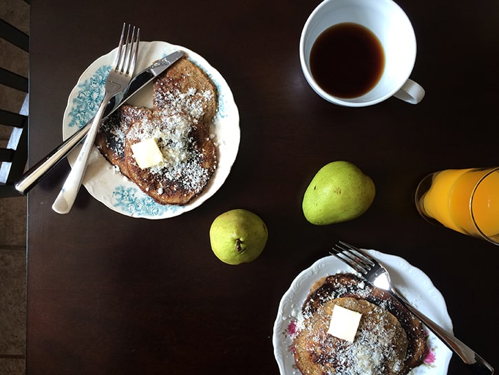 Paleo pancakes topped with coconut, plus pears, fresh orange juice, and coffee.