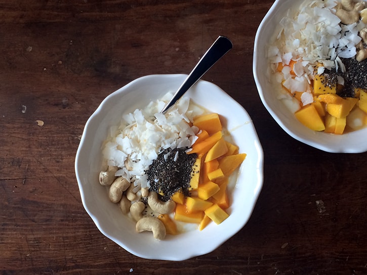 Yogurt with fresh mango, flaked coconut, cashews, chia seeds, and a drizzle of honey.