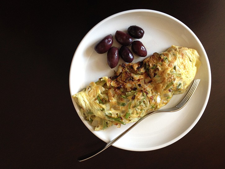 Zucchini, onion, and garlic omelet with black olives on the side