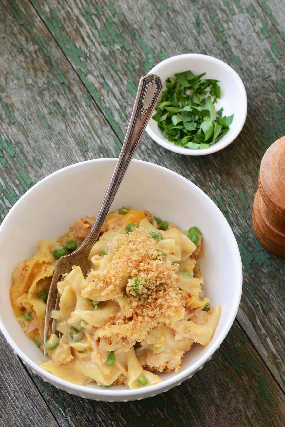 bowl of cheesy tuna noodle casserole on green wooden table