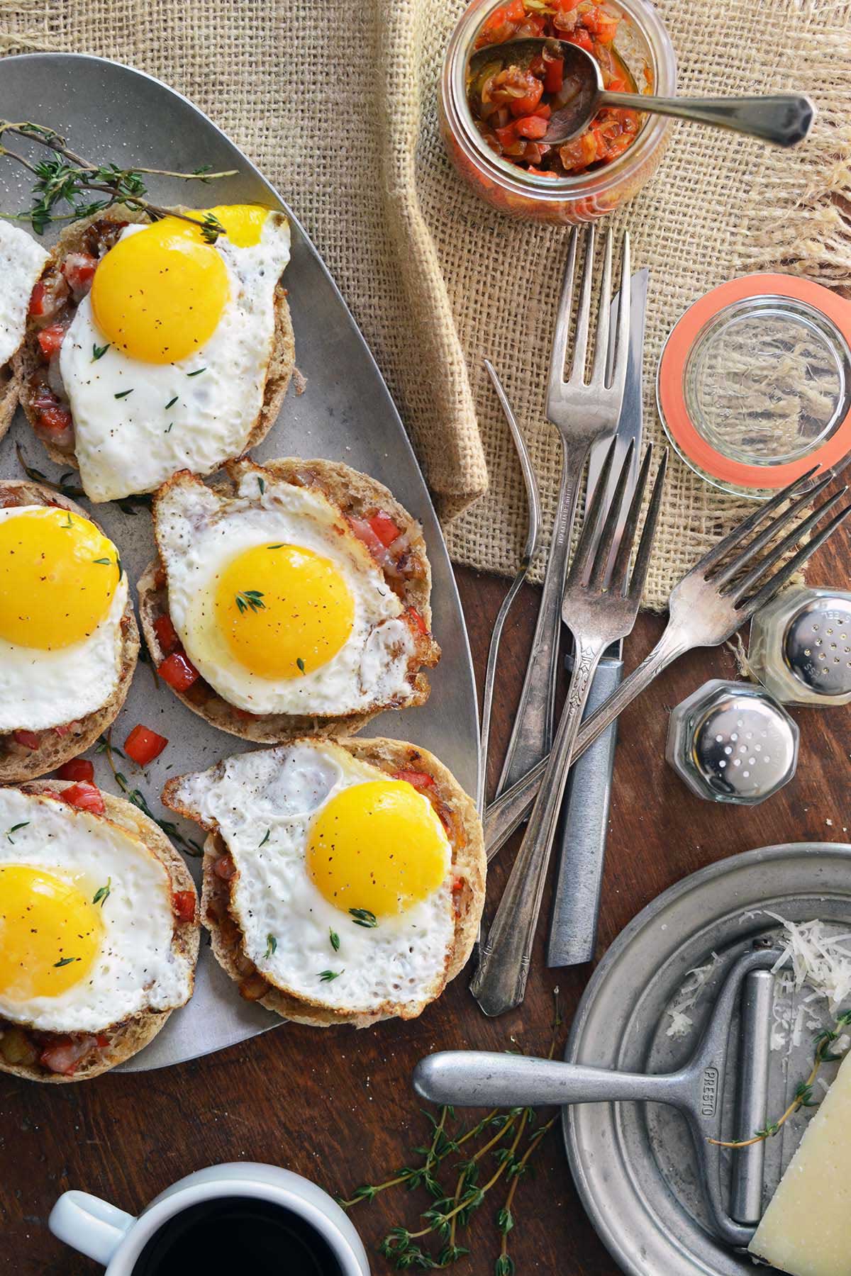 brunch spread with fried eggs with runny yolks on English muffins with manchego and red bell pepper compote