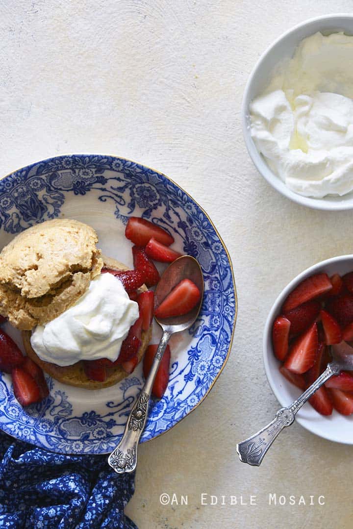 Top View of Gluten Free Strawberry Shortcake in Blue and White Flowered Bowl with Bowl of Strawberries on White Table