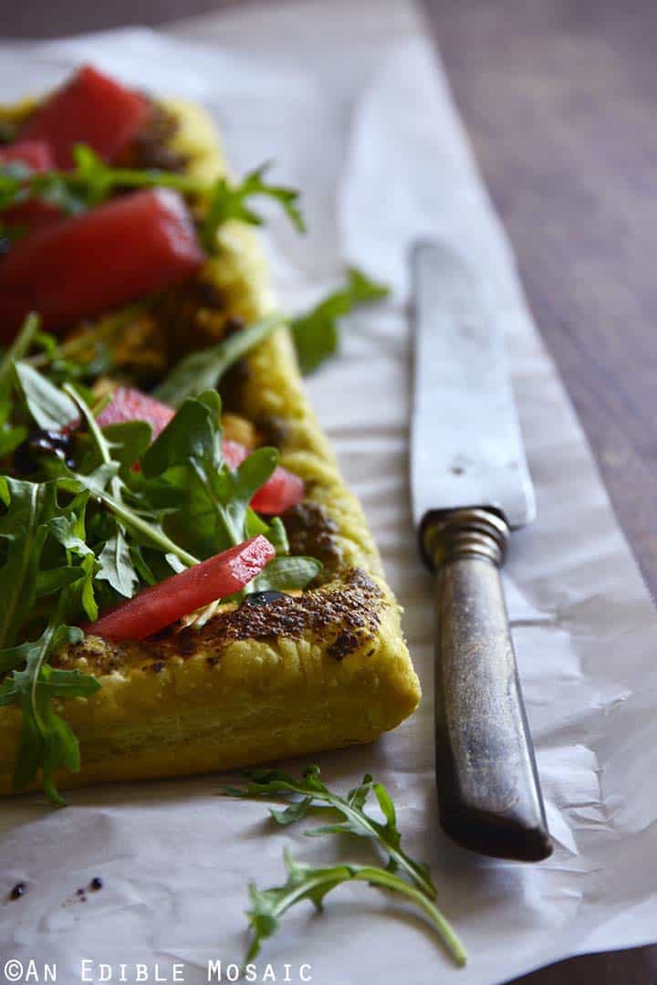 Garlic and Chive Goat Cheese and Pesto Puff Pastry Tart with Arugula, Watermelon, and Strawberry-Balsamic Drizzle on Parchment Paper