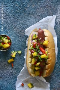 Hot Dogs with Hawaiian-Inspired Pineapple Jalapeno Teriyaki Relish on Blue Background Top View
