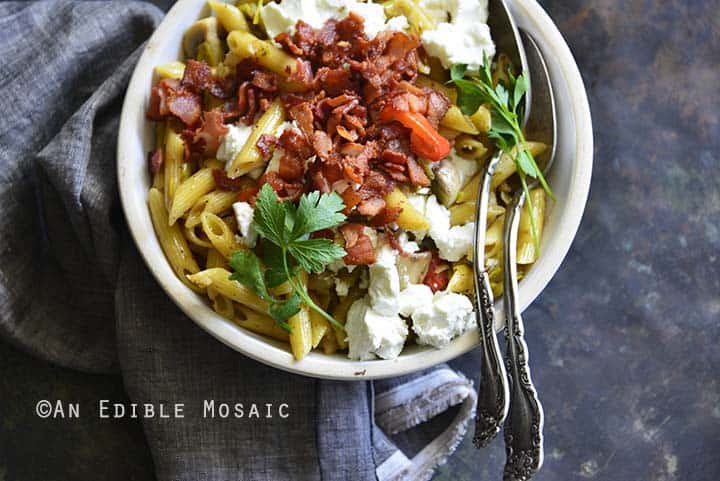 Warm Caramelized Leek Pasta Salad with Bacon and Goat Cheese on Metal Background