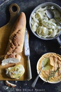 Spread of Baked Schloss Cheese with Melted White Wine Onions with Baguette