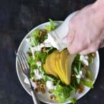 Pouring The Best Creamy Blue Cheese Dressing on Pear Hazelnut Salad