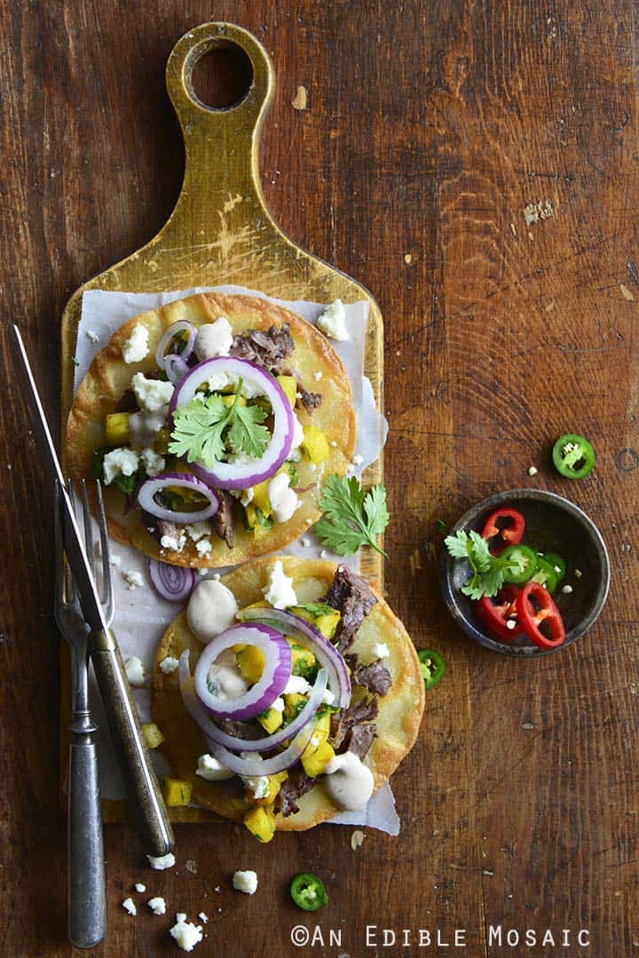 Short Rib Tostadas with Pineapple Salsa and Cotija on Wooden Cutting Board