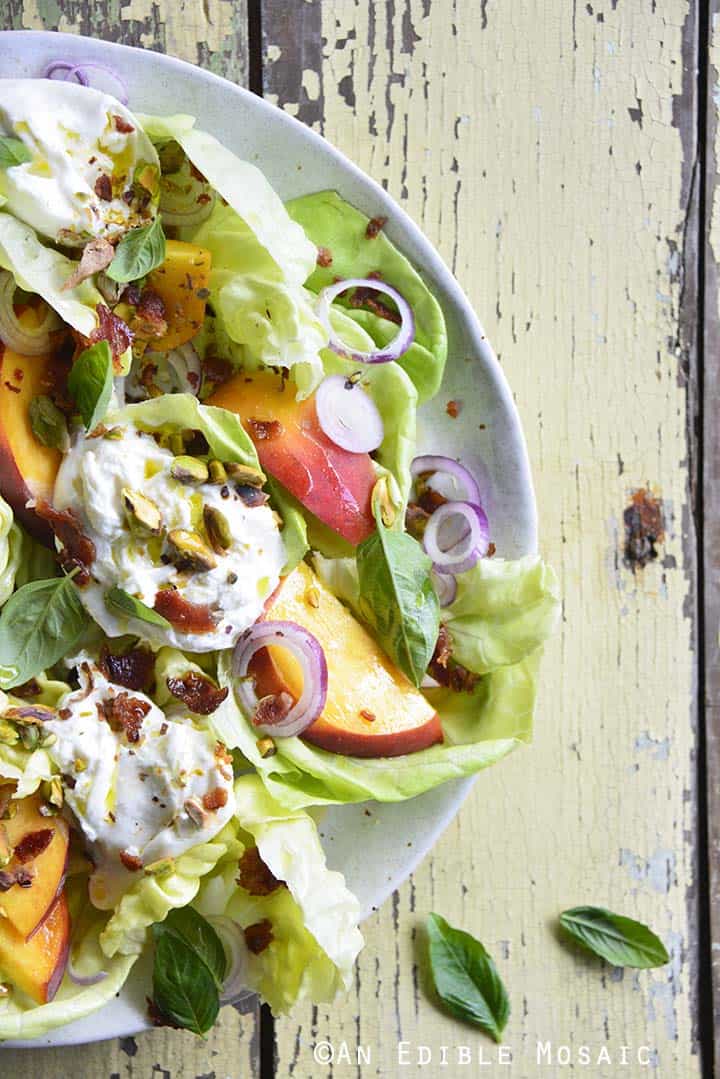 Burrata Peach Salad with Butter Lettuce, Basil, and Pistachio on Yellow Wooden Table