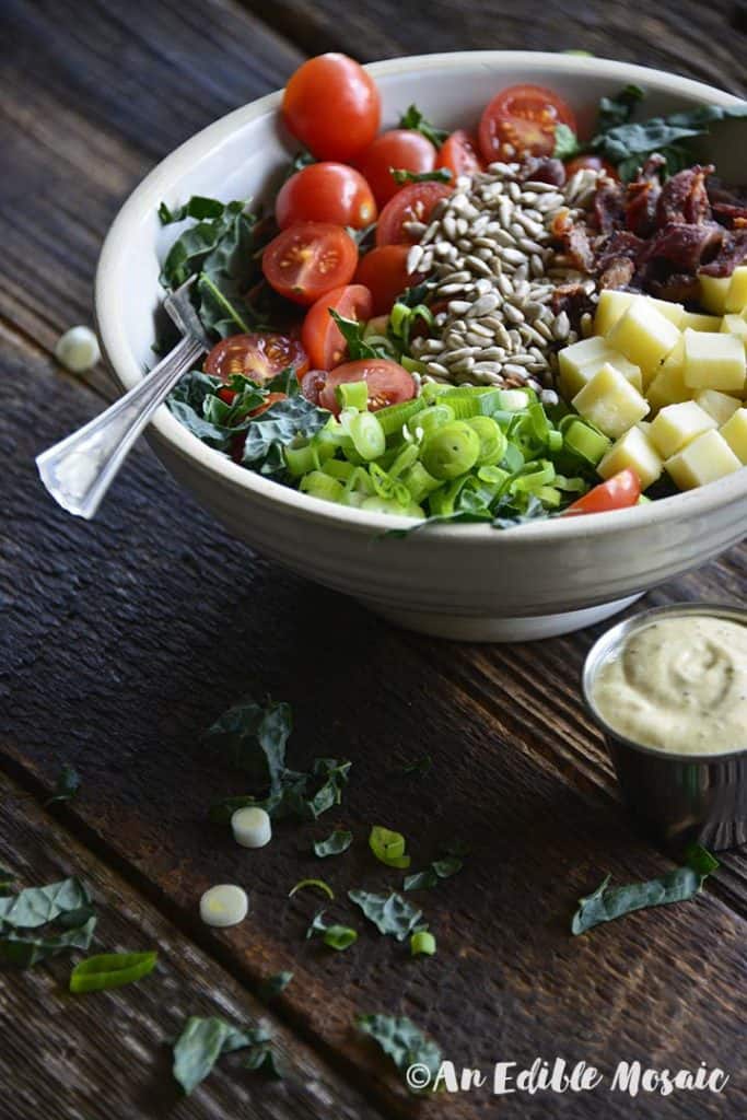 Chopped Kale Salad in White Ceramic Bowl with Vintage Fork on Wood Table