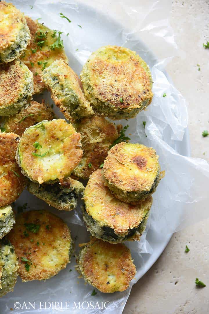Keto Crispy Baked Zucchini Slices on Wax Paper on White Plate on Creamy Marble Background
