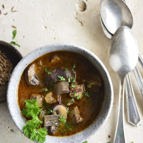 Overhead View of Leftover Steak Soup with Mushrooms in Ceramic Bowl with Vintage Spoons