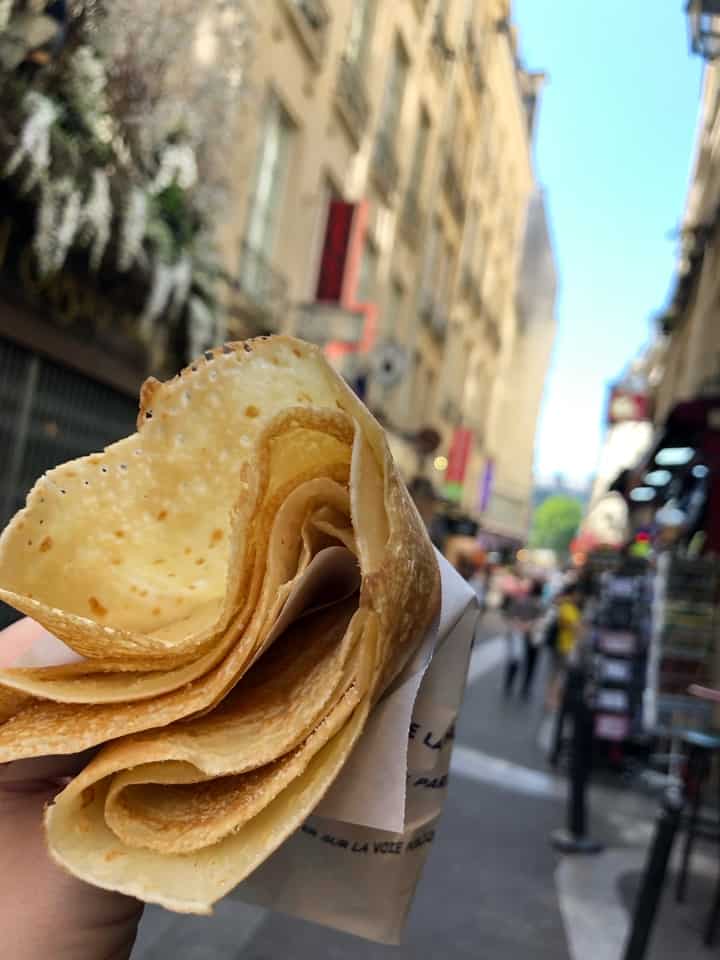 Hand Holding Crepe with Paris Street in Background