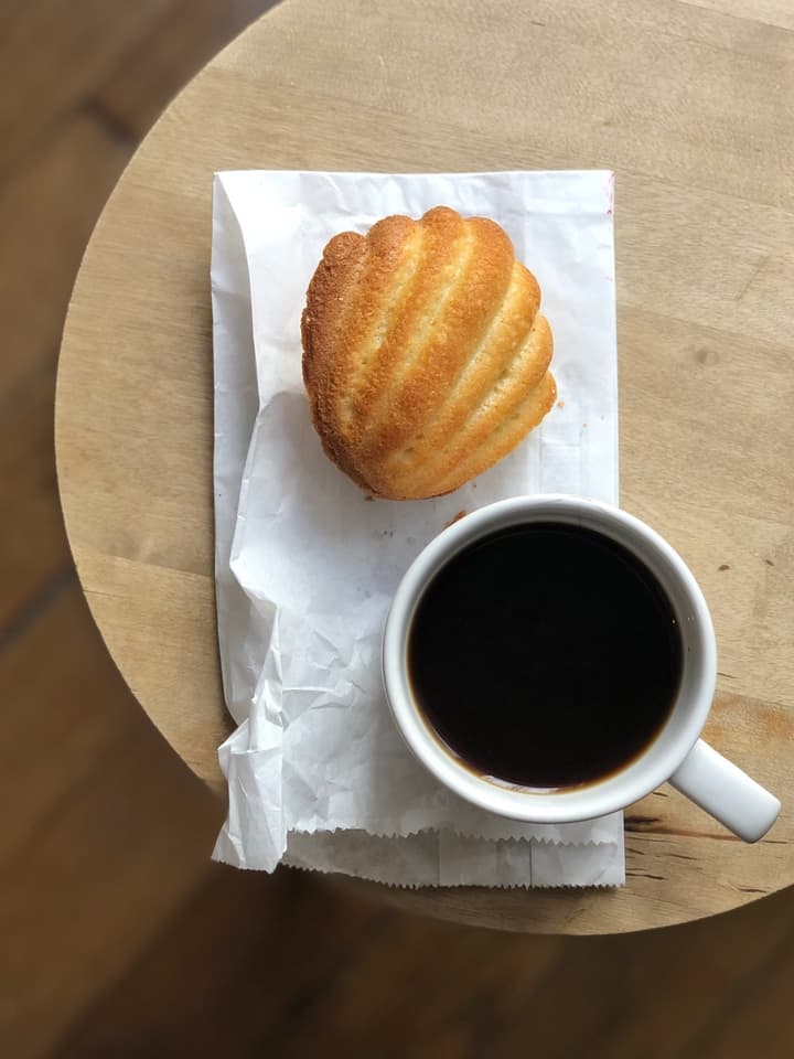 Madeleine on White Paper Bag with Cup of Coffee