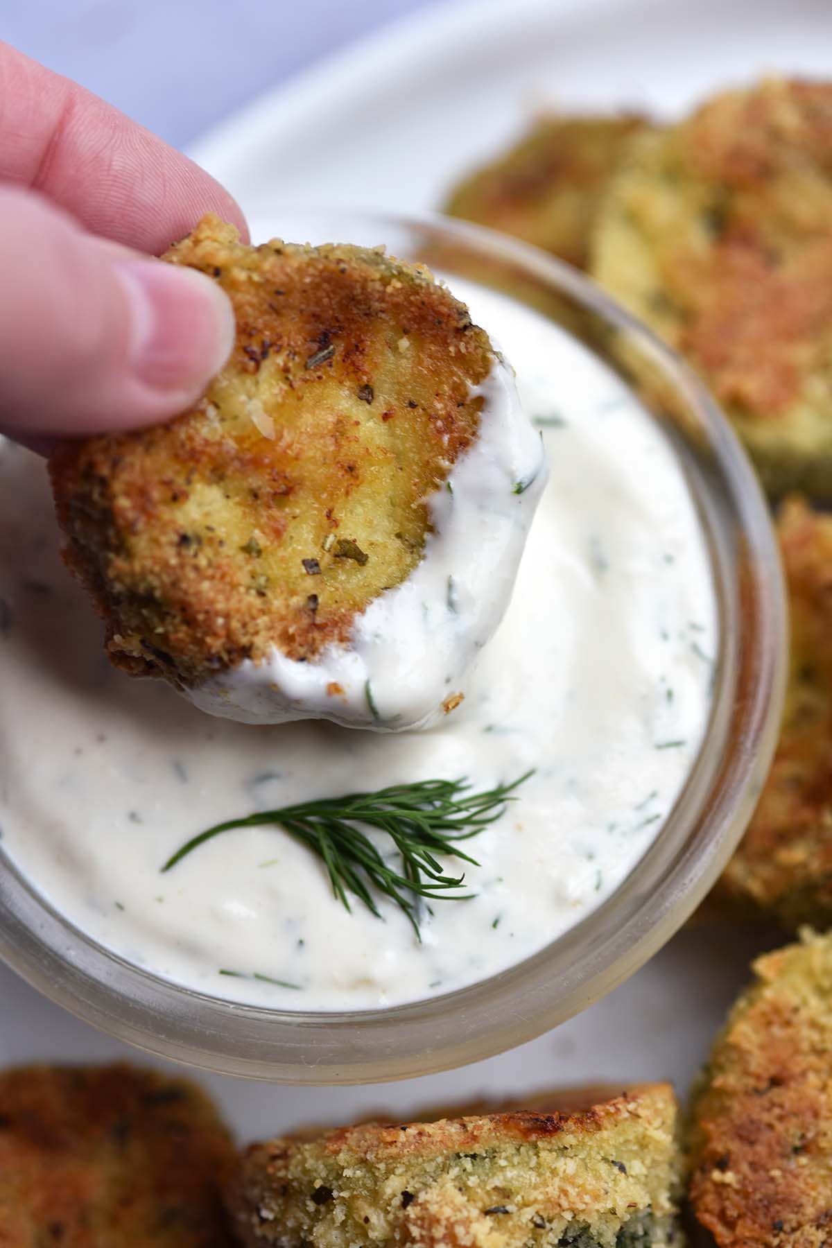 dipping keto crispy oven baked zucchini slice into homemade ranch dressing