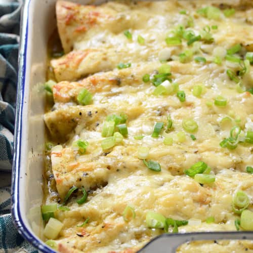 Creamy Chicken and Kale Enchiladas with Salsa Verde in White Casserole Dish