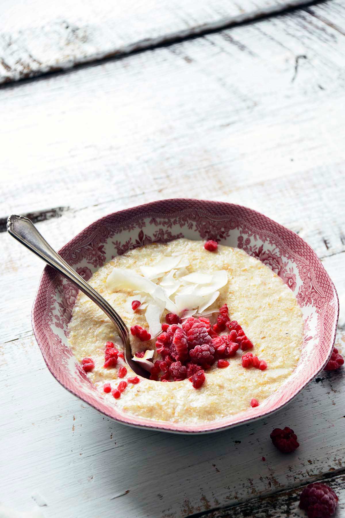 front view of bowl of low carb keto noatmeal porridge hot cereal with frozen raspberries and coconut