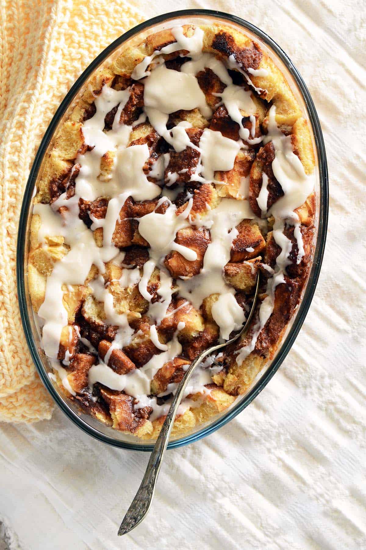 overhead view of cinnamon roll bread pudding in casserole dish on cream tablecloth