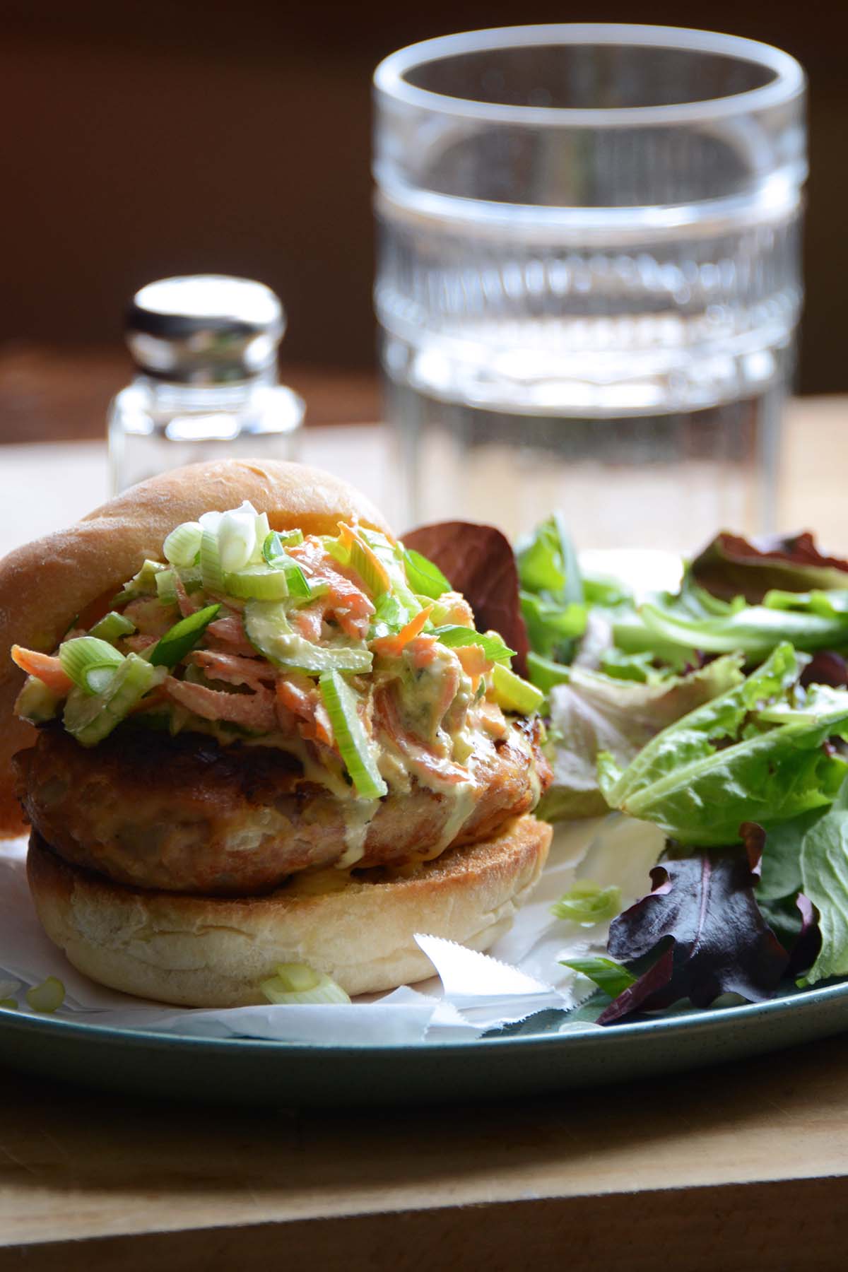front view of buffalo chicken burger on bun with blue cheese slaw on platter