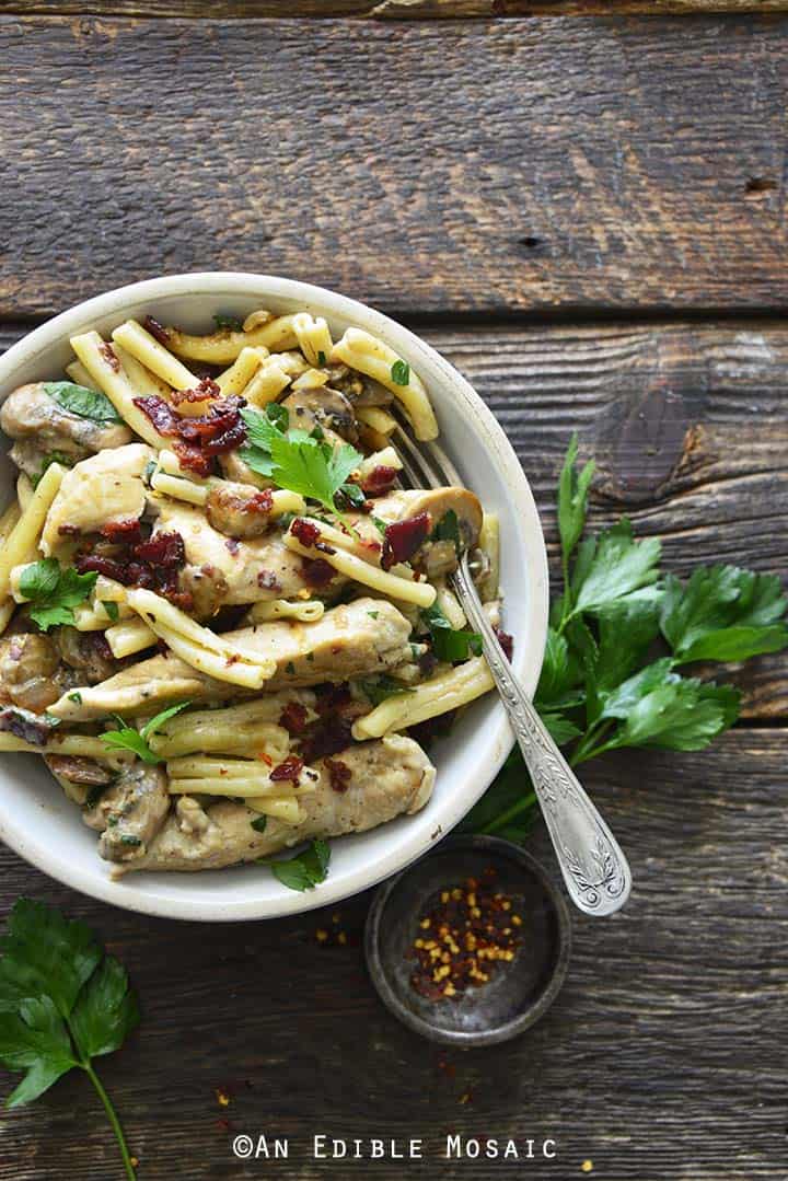 Pasta cremosa di pollo ai funghi in ciotola bianca con forchetta Vintage