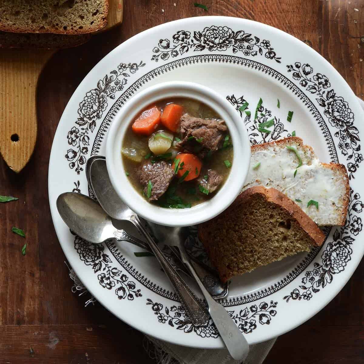 guinness and beef stew overhead view in serving bowl on flowered pottery plate