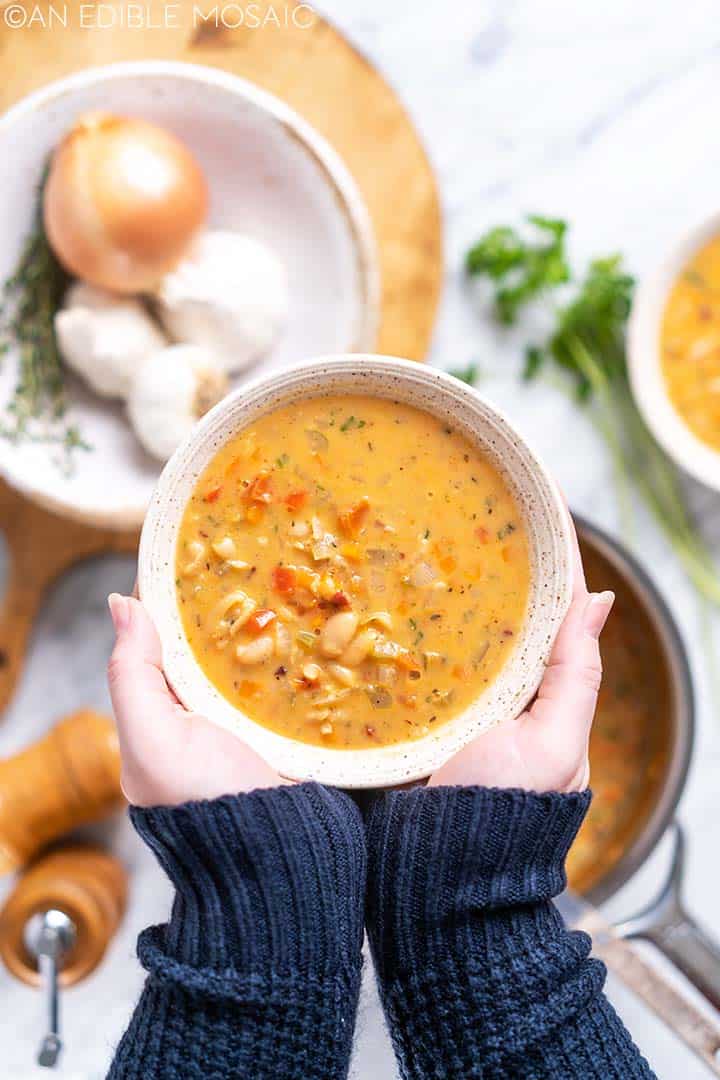 hands holding bowl of healthy white bean soup