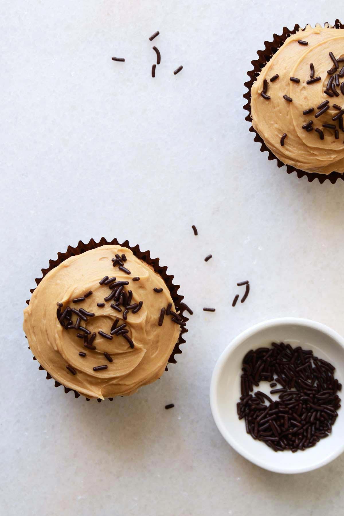 top view of two guinness cupcake with chocolate sprinkles on marble countertop