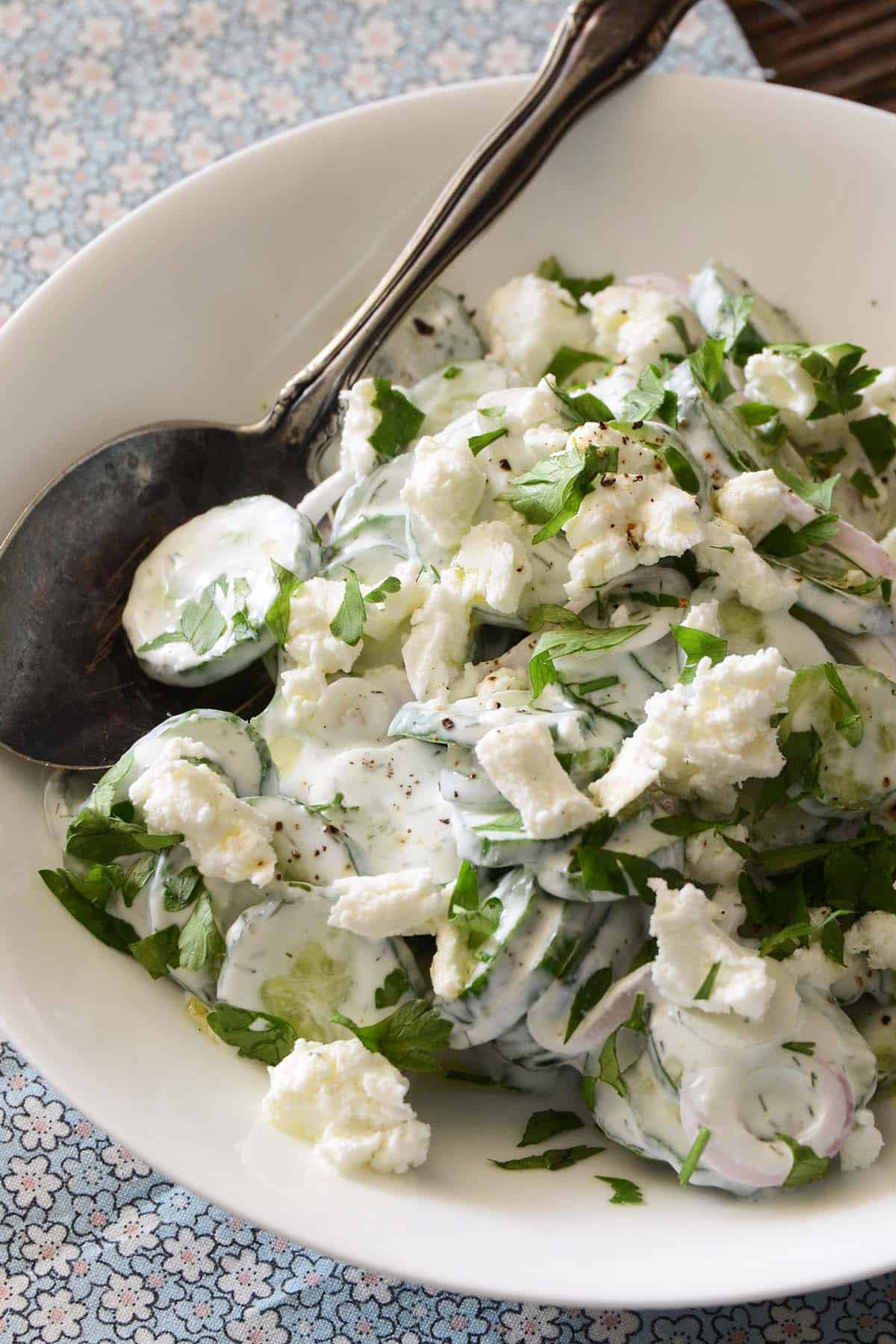 close up front view of creamy cucumber salad with red onion