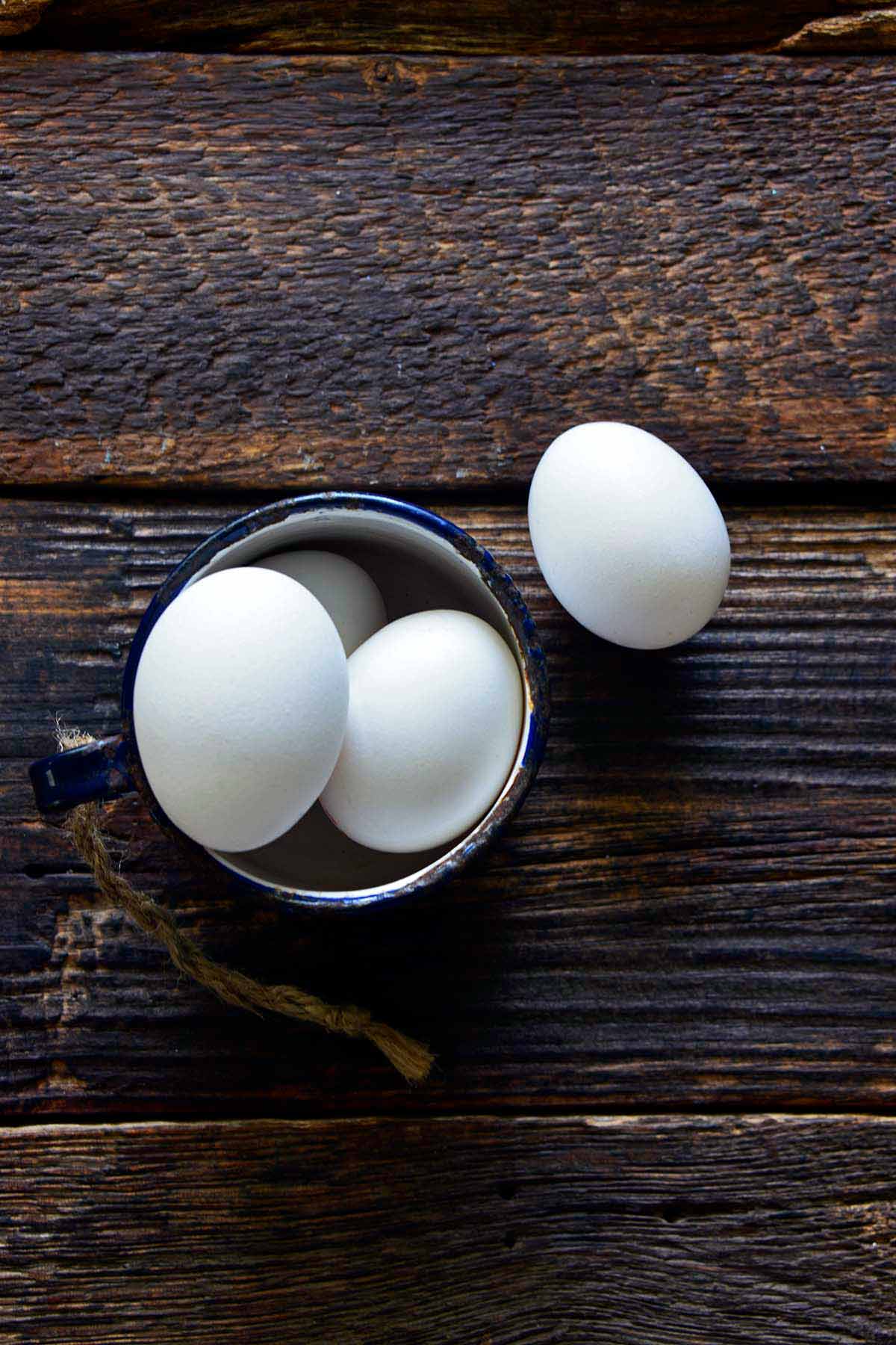 eggs in enamel cup on rustic wooden table