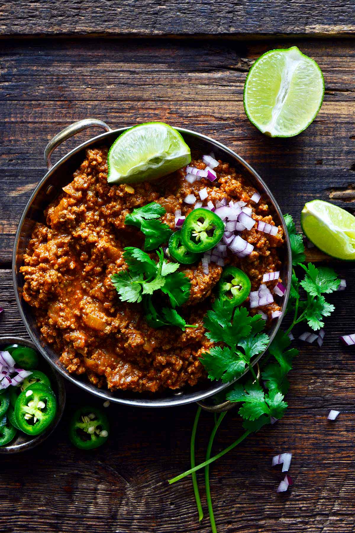 overhead view of Kheema Pav in Indian bowl with fresh cilantro and red onion on top