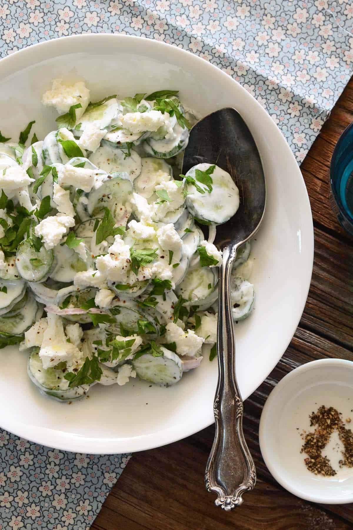 top view of creamy cucumber salad with dill in white bowl