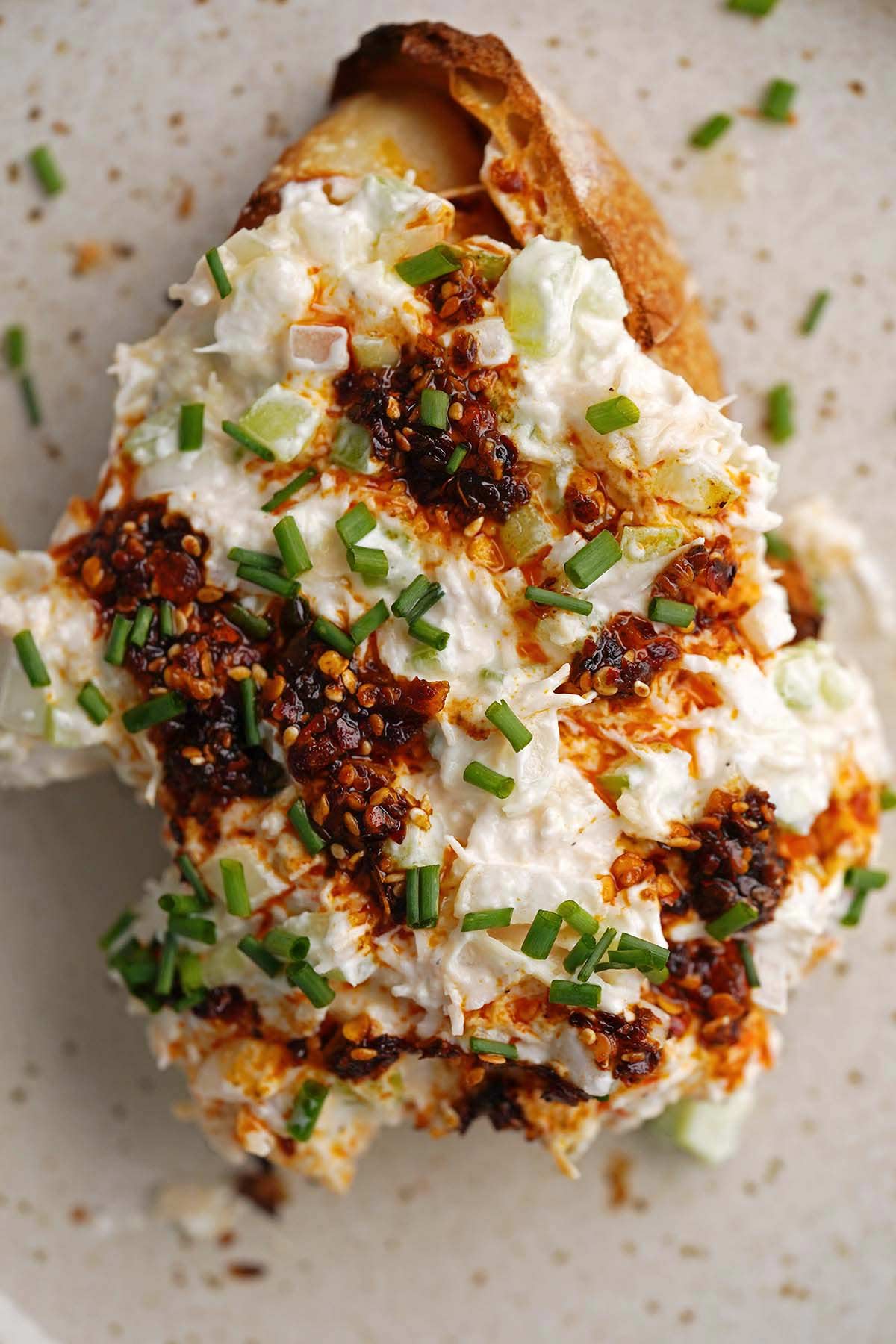 top view of the best canned chicken salad on sourdough bread topped with chili crisp honey and chives