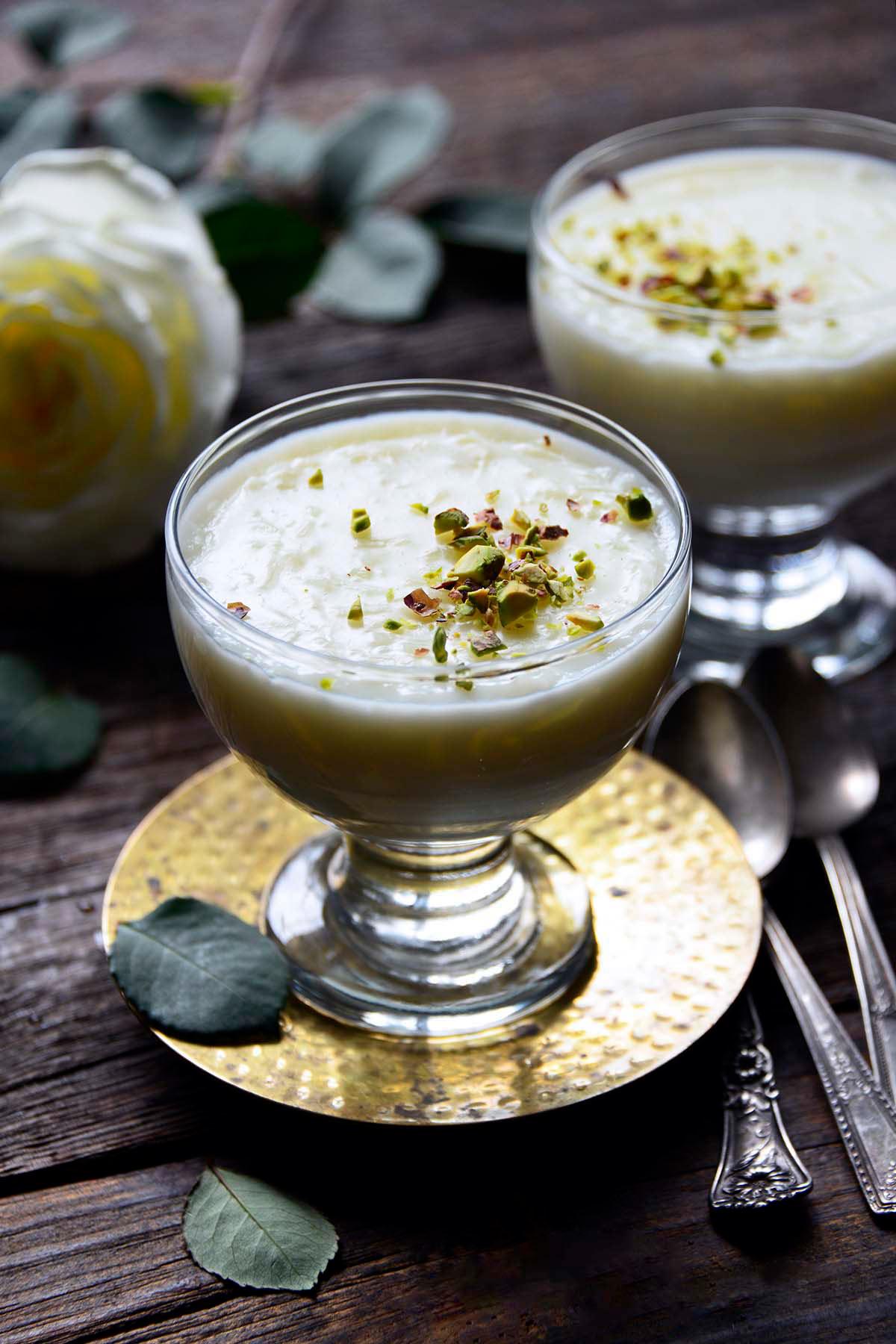 front view of glass dessert dishes with simple rice pudding topped with pistachios