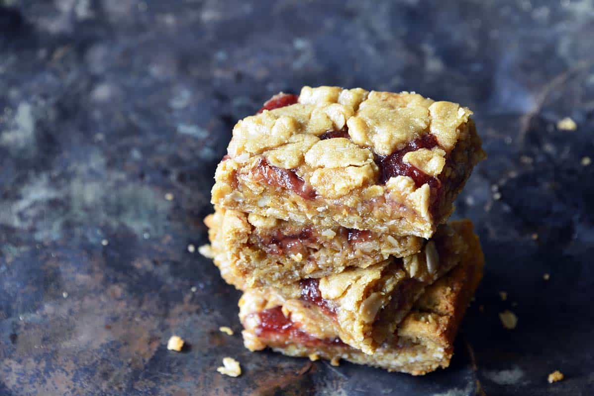 3 stacked peanut butter jelly bars on blue background