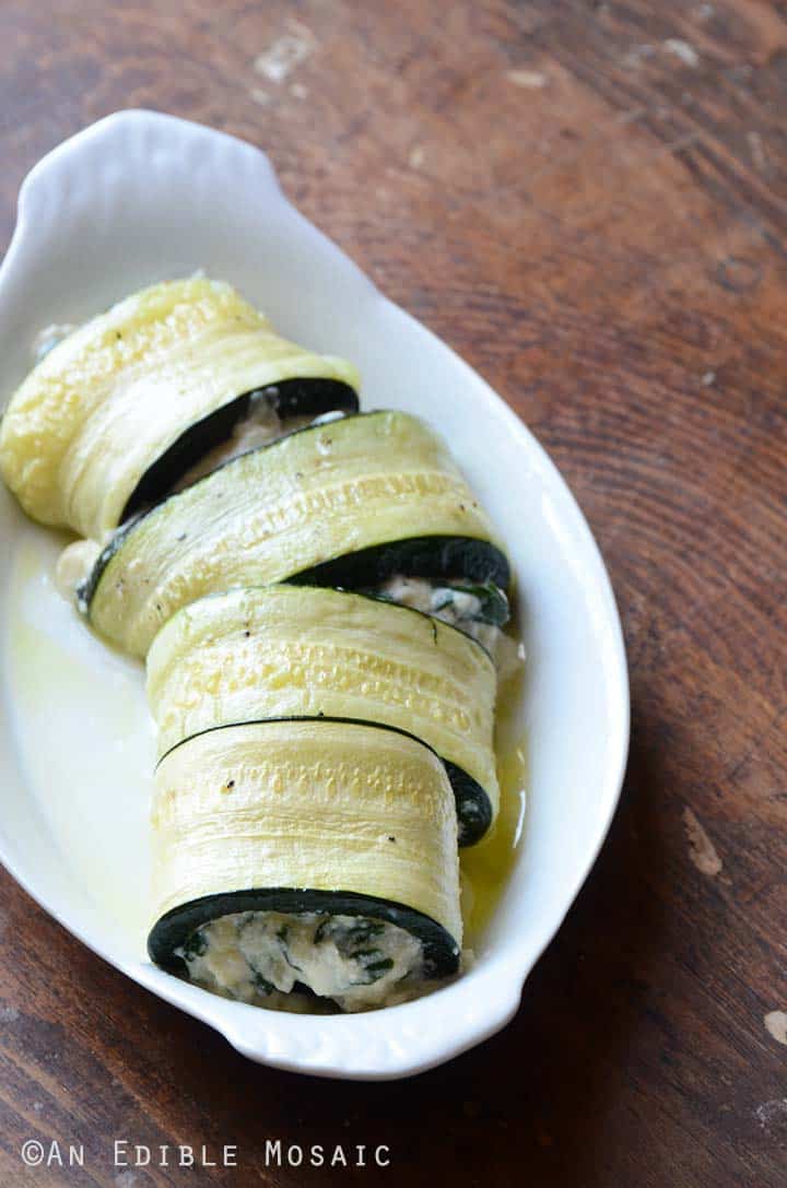 Making Zucchini Roll Ups in White Dish on Top of Dark Wooden Table