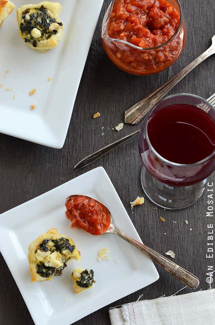 Spanakopita Puff Pastry Bites on White Plate with Tomato Sauce and Wine Glass